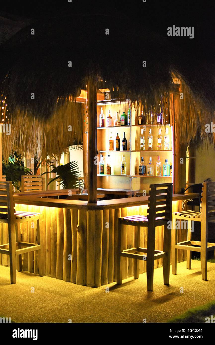 Eine tropische Bar im Freien mit Alkoholflaschen und leeren Stühlen in einem Resorthotel während des nächtlichen Ferienurlaubs Stockfoto