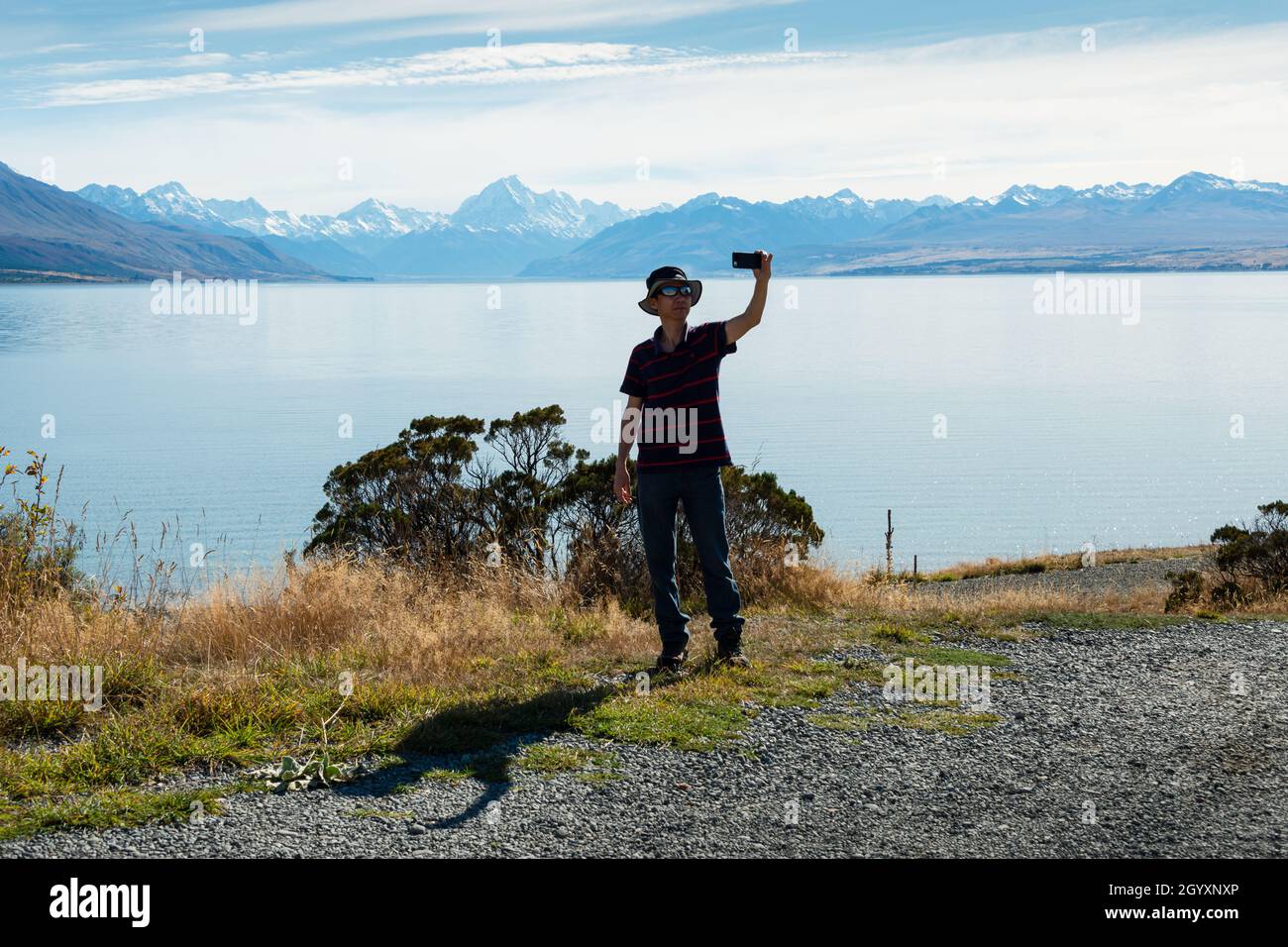 Touristen, die Selfie-Fotos am Ufer des Lake Pukaki vor dem Hintergrund des Mt Cook und der Südalpen, Südinsel, machen. Vertikales Format Stockfoto