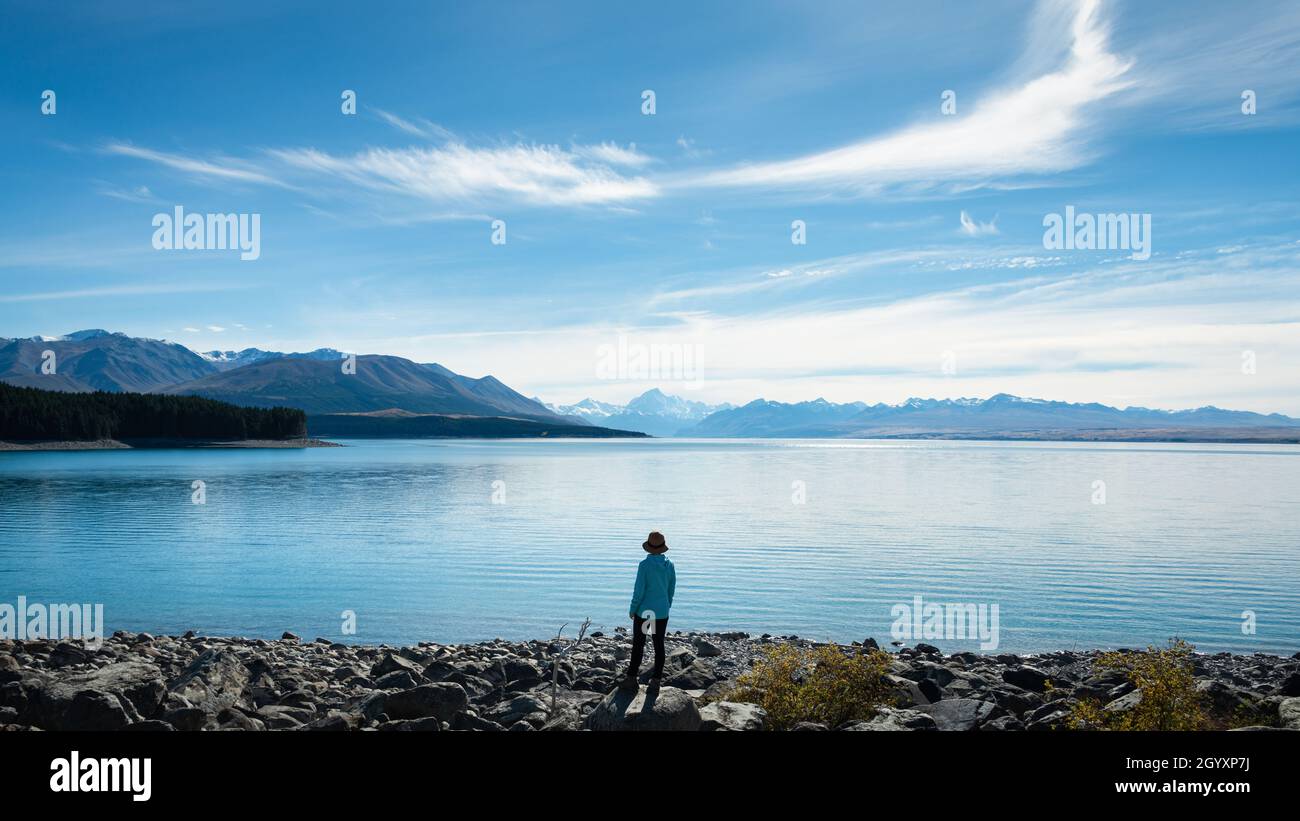 Frau, die am Ufer des Lake Pukaki steht und die Aussicht auf Mt Cook und die südlichen Alpen, Südinsel, genießt. Stockfoto