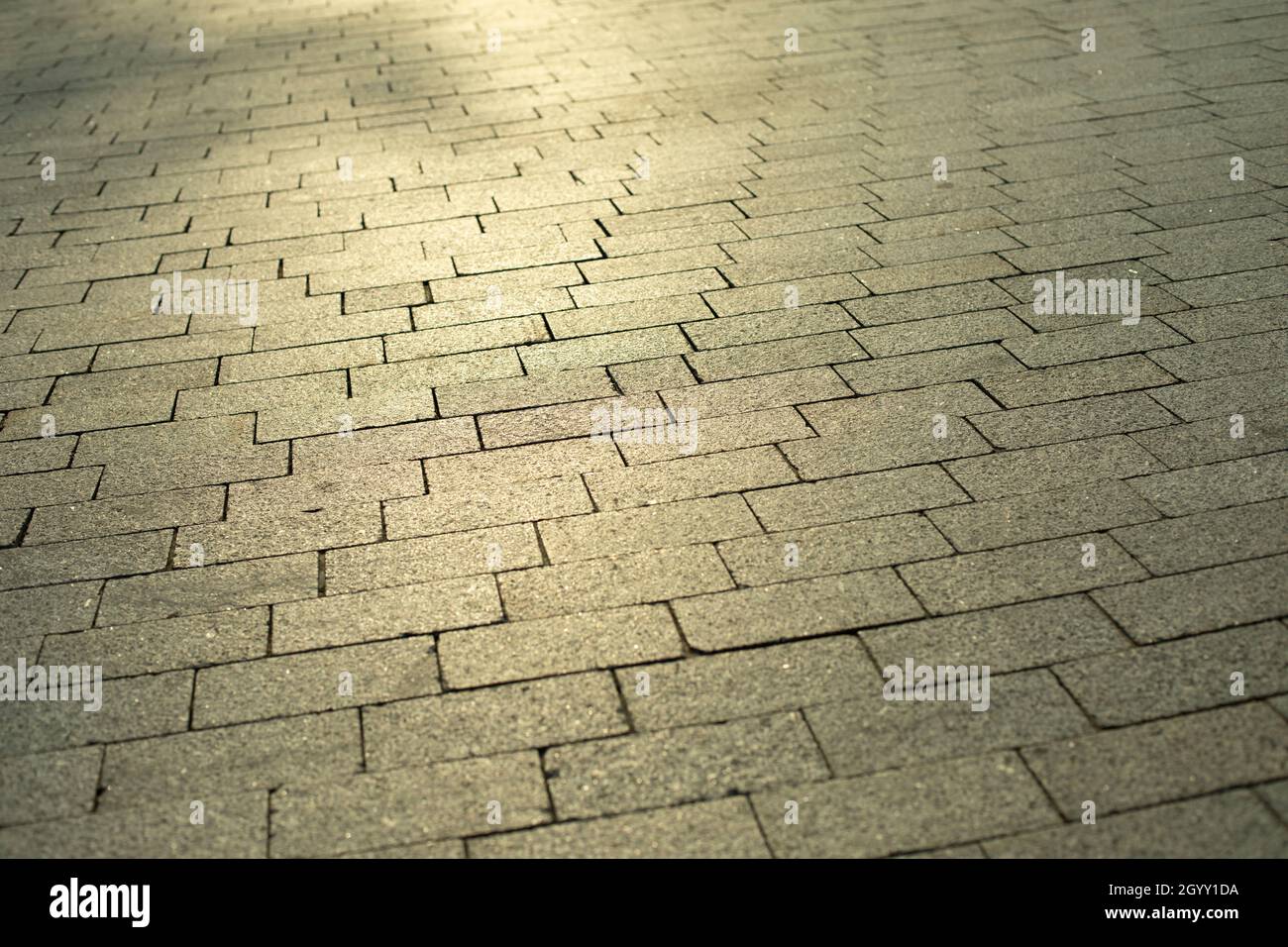 Die sich wiederholende Textur des Steins in der Fußgängerzone. Steinblöcke werden in einer Reihe gelegt. Stockfoto