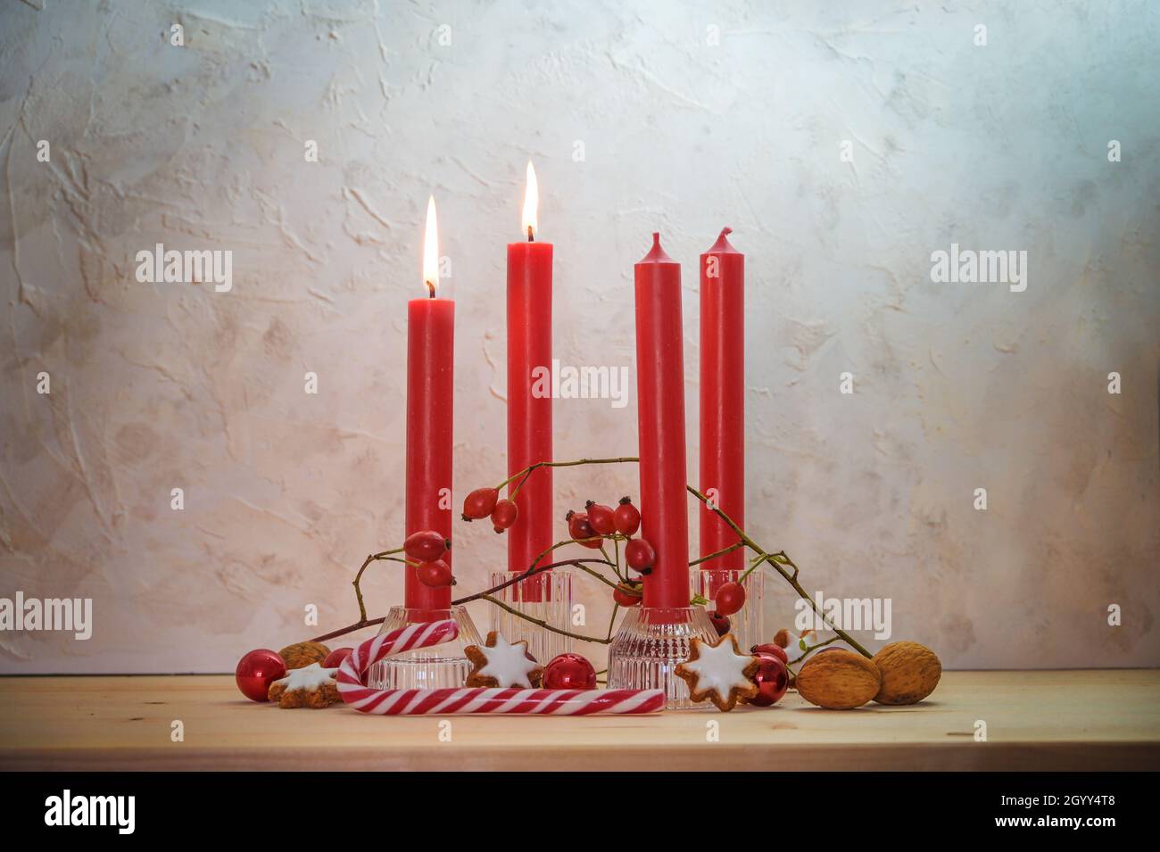 Vier rote Kerzen, zwei werden für den zweiten Sonntag vor Weihnachten angezündet, Adventsdekoration auf einem Holztisch gegen eine rustikale Wand, Kopierraum, ausgewählt Stockfoto
