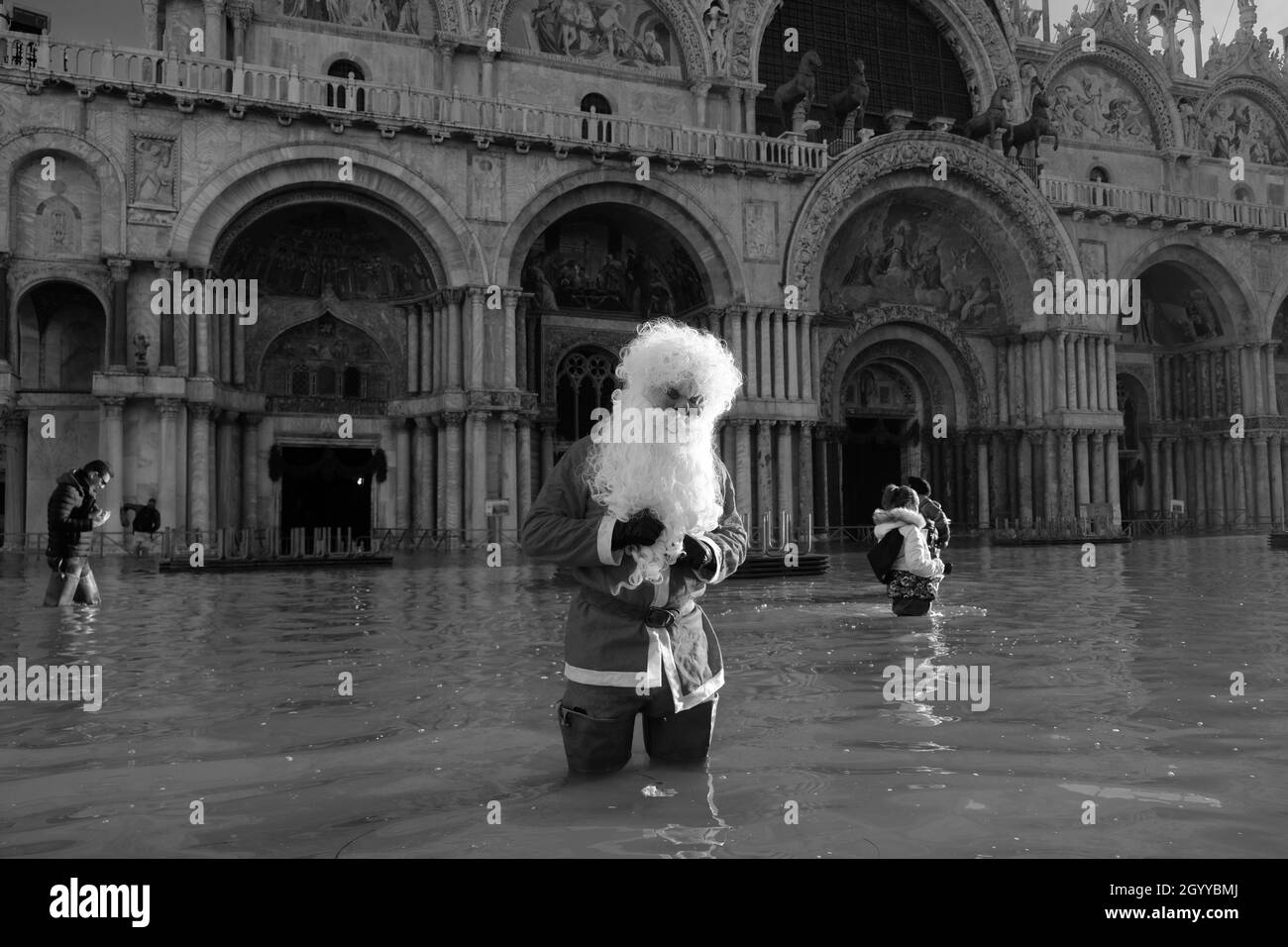 Ein Mann, der als Weihnachtsmann gekleidet ist, wat während der Flut in Venedig, Italien, am 23. Dezember 2019 durch den Markusplatz. Stockfoto