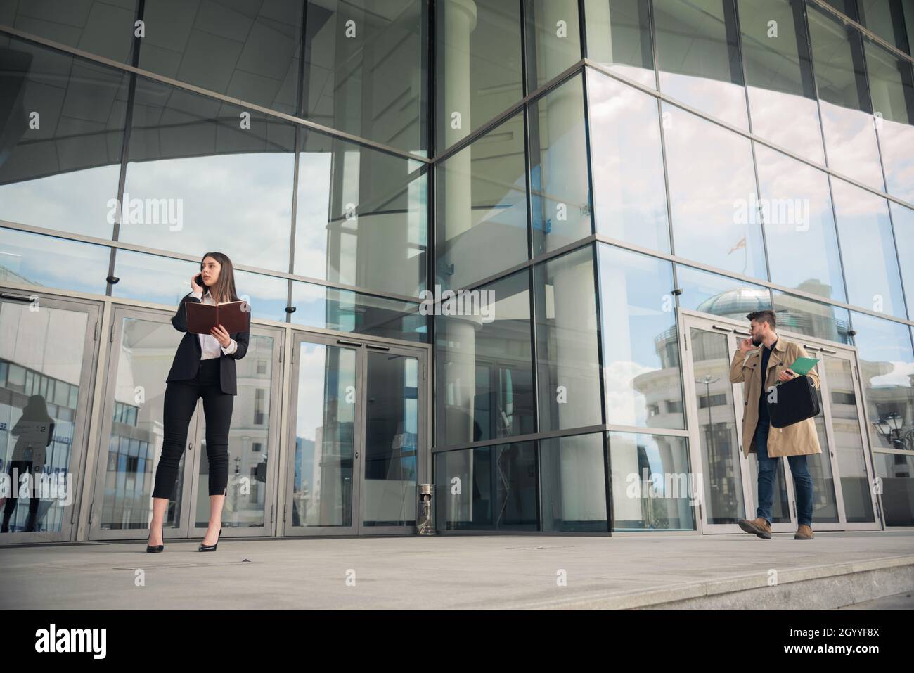 Zwei Geschäftsleute telefonieren vor dem Unternehmen Stockfoto