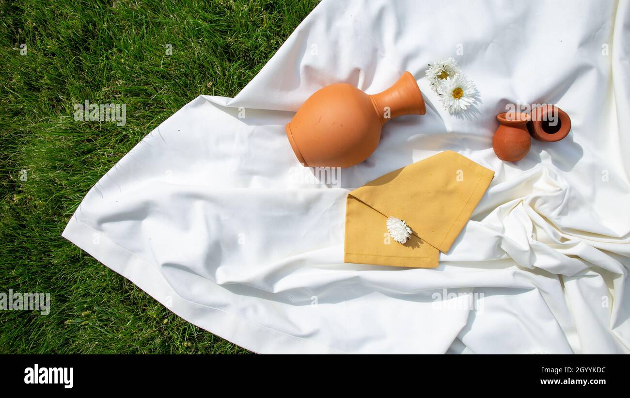Ein Tonkrug auf einem weißen Tuch auf dem Gras. Draufsicht. Stockfoto