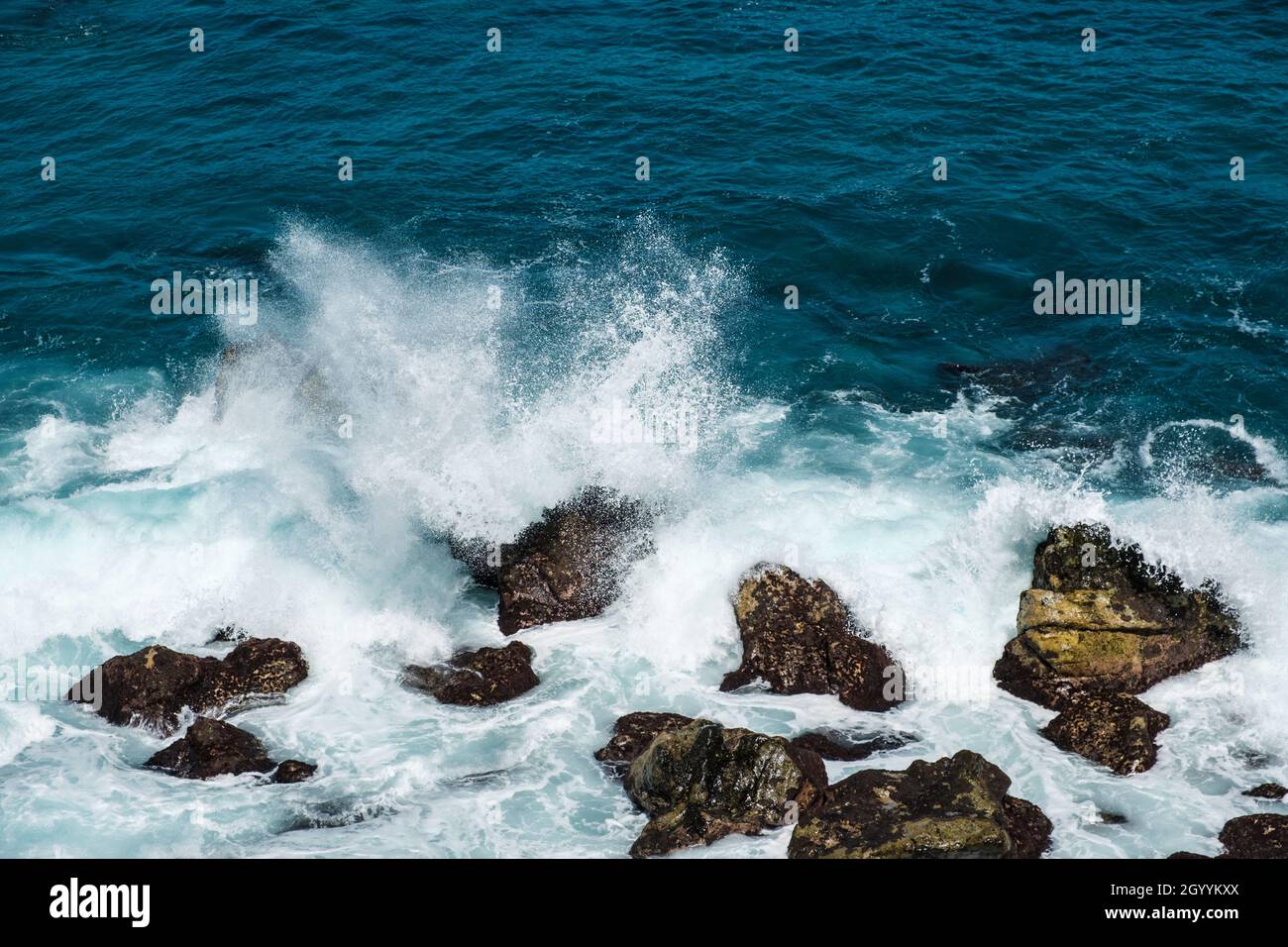 Raue Meereswellen, die an der Küste oder am Strand auf Felsen krachen Stockfoto