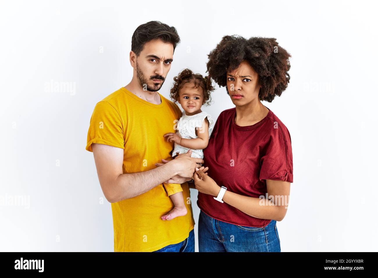 Interracial junge Familie von schwarzer Mutter und hispanischen Vater mit Tochter skeptisch und nervös, runzelte wegen des Problems. Negative Person. Stockfoto