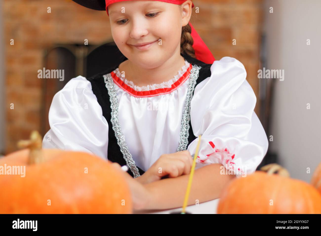 Halloween. Ein Kind zu Hause bereitet sich auf eine Party vor und zieht einen Kürbis an. Kleines Mädchen in einem Piratenkostüm. Stockfoto