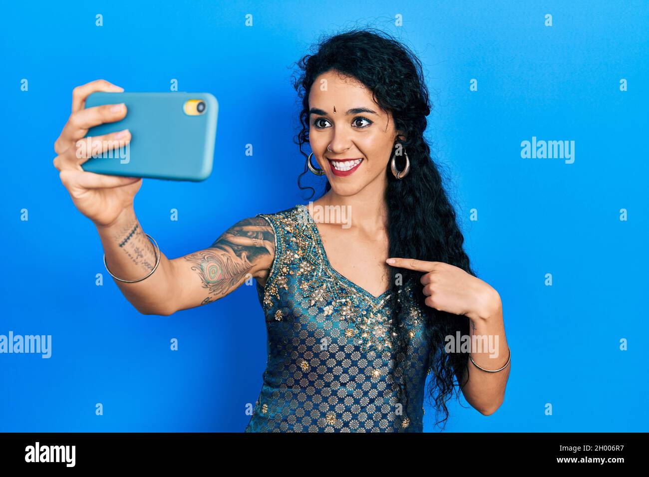Junge Frau in Bindi und traditionellem Kurta-Kleid, die ein Selfie-Foto mit einem lächelnden Smartphone macht, das glücklich mit Hand und Finger zeigt Stockfoto