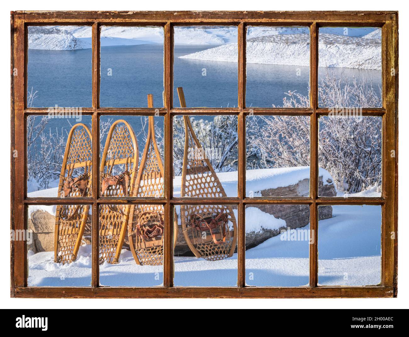 Klassische Schneeschuhe aus Holz in der Winterlandschaft eines Bergsees, von einem Vintage-Schiebefenster aus gesehen Stockfoto