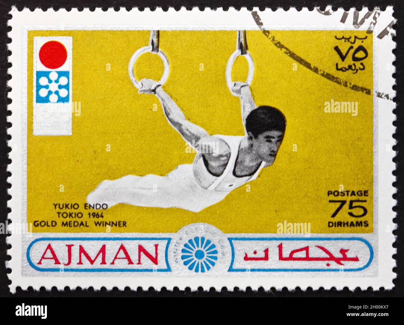 AJMAN - UM 1964: Eine auf Ajman gedruckte Briefmarke zeigt Yukio Endo, japanische Kunstturnerin, Gewinner der Tokio 1964 Goldmedaille, um 1964 Stockfoto