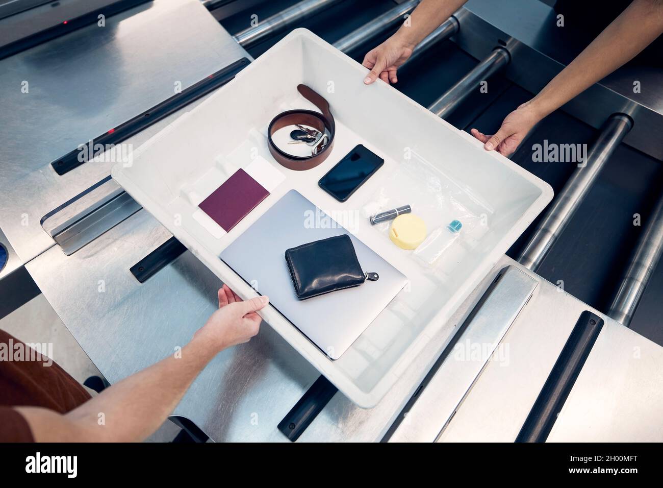 Persönliche Gegenstände, Flüssigkeiten und Laptop im Container während der Kontrolle bei der Sicherheitskontrolle des Flughafens vor dem Flug. Stockfoto