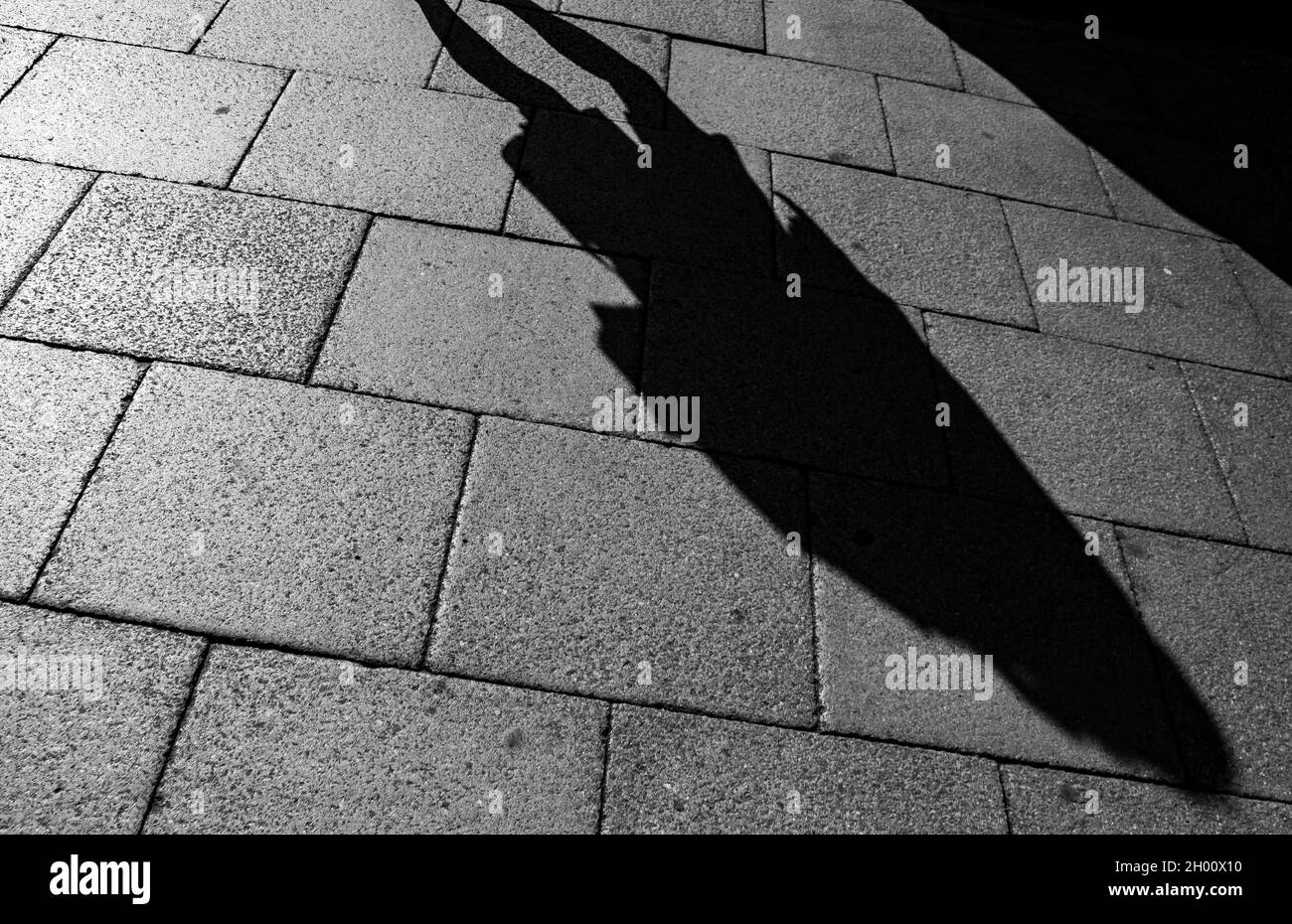 Die niedrige Sonne wirft Startschatten von Menschen auf den Straßen von Cambridge Stockfoto