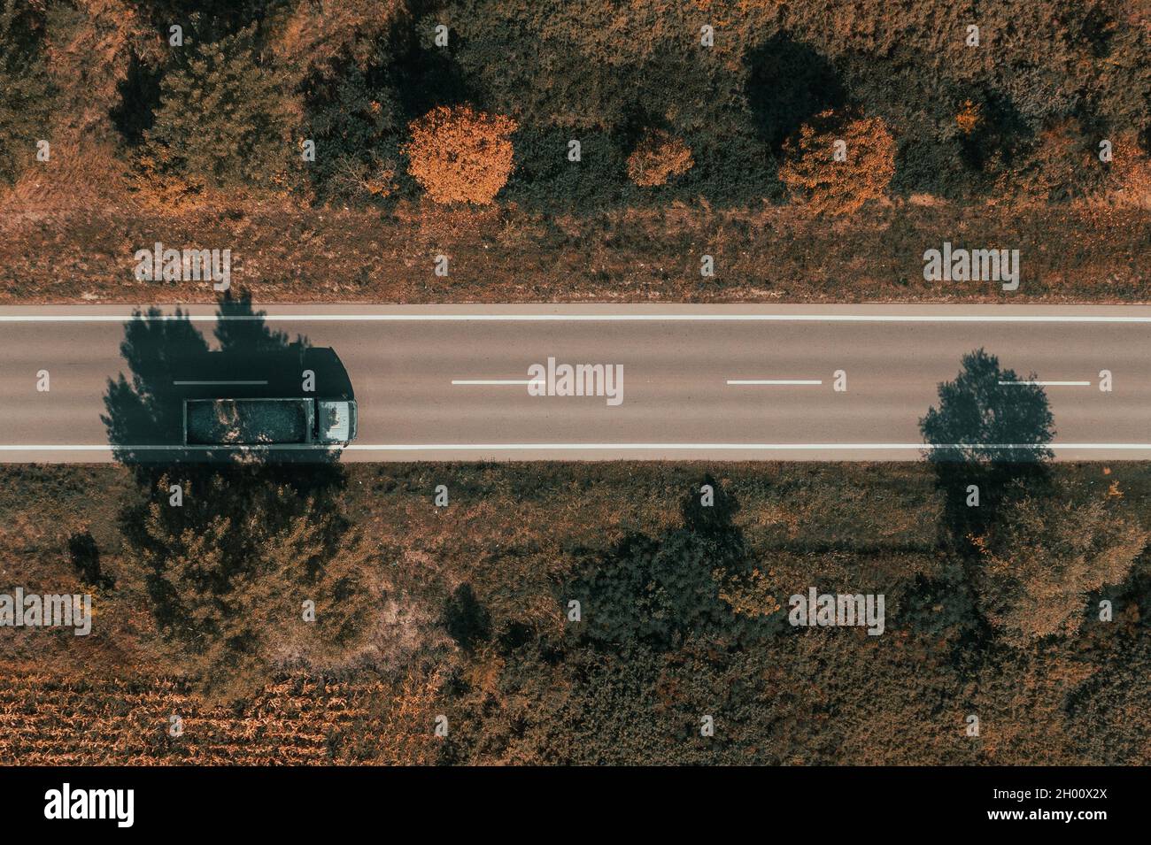 Luftaufnahme eines LKW mit Wagen voller Kiesel, Drone-Fotografie des Fahrzeugs auf der Straße von oben nach unten Stockfoto