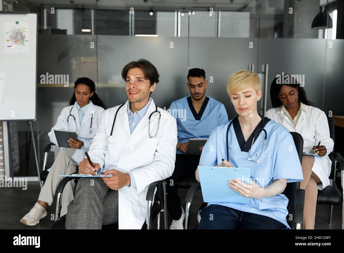 Aus- und Weiterbildung für Fachkräfte im Gesundheitswesen. Multiethnische Gruppe von Ärzten in Arbeitskleidung, die an einer medizinischen Konferenz oder Schulung an der cli teilnehmen Stockfoto
