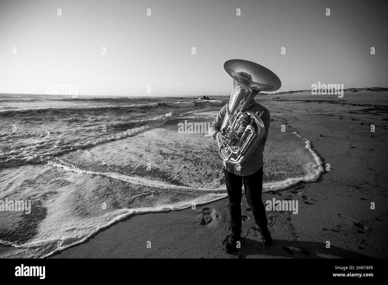 Ein Musiker mit einer Tuba an der Küste. Schwarzweiß-Foto. Stockfoto