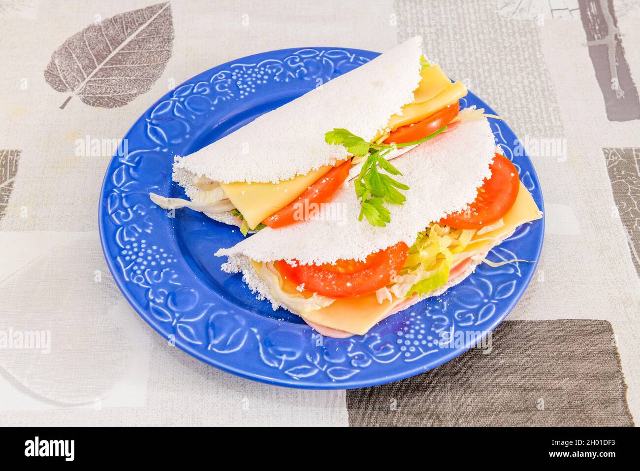 Brasilianisches Sandwich mit Tomaten, Salat, gekochtem Schinken und  Käsescheiben, eingewickelt in ein Tapioka-Omelett Stockfotografie - Alamy