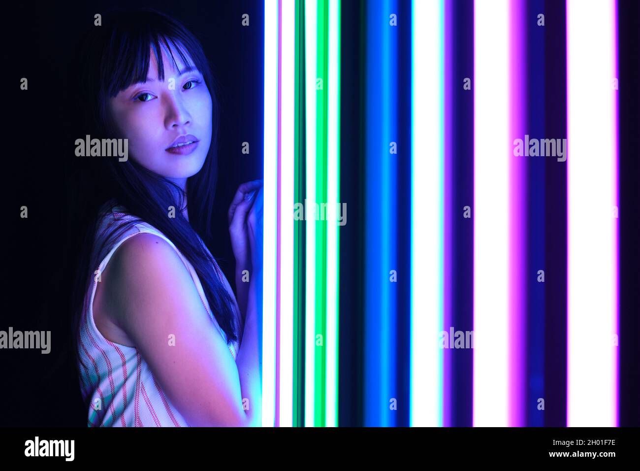Junge asiatische Frau posieren mit bunten hellen Neonlichtern im Studio. Stockfoto