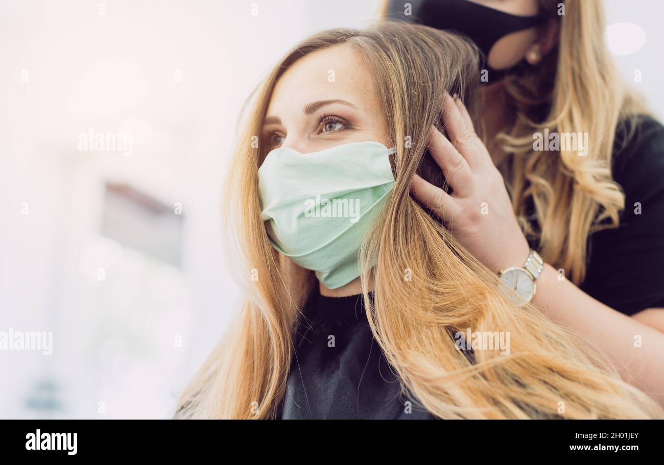 Frau mit frischem Haar Styling in Friseurladen mit Gesichtsmaske Stockfoto