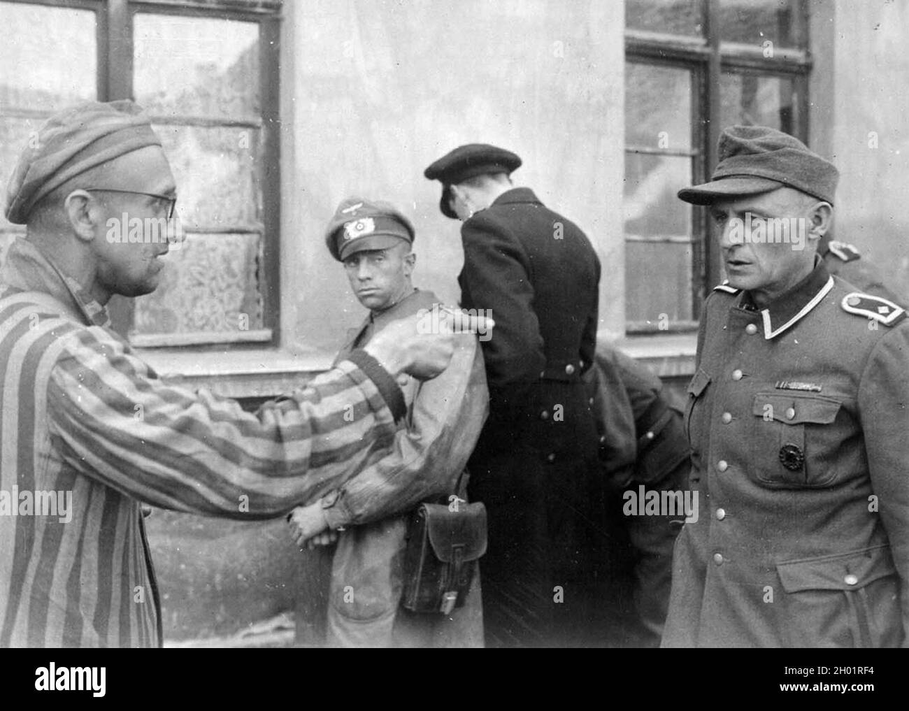 Ein russischer Überlebender, der von der 3. Panzerdivision der ersten US-Armee befreit wurde, identifiziert einen ehemaligen Lagerwächter, der am 14. April 1945 im Konzentrationslager Buchenwald in Thüringen Gefangene brutal schlug Stockfoto