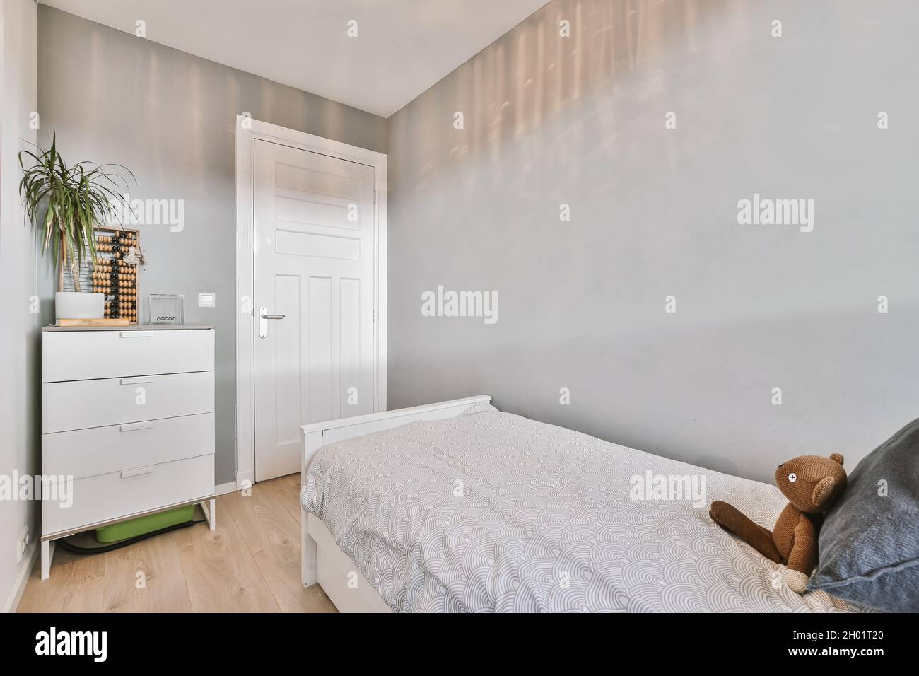 Eine Innenaufnahme eines Kinderzimmers mit einem kleinen Bett, einem weißen Kleiderschrank und einem Holzboden Stockfoto