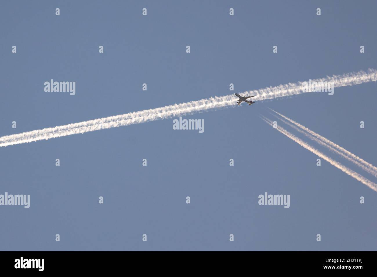 Verkehr am Himmel. Ein Flugzeug überquert den Kondensstreifen, den ein anderes Flugzeug einige Sekunden zuvor am Himmel markiert hat. Am Frühen Morgen Stockfoto