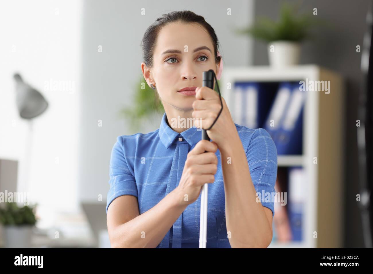 Blinde Frau mit abwesendem Blick blickt in die Ferne und hält den Stock Stockfoto