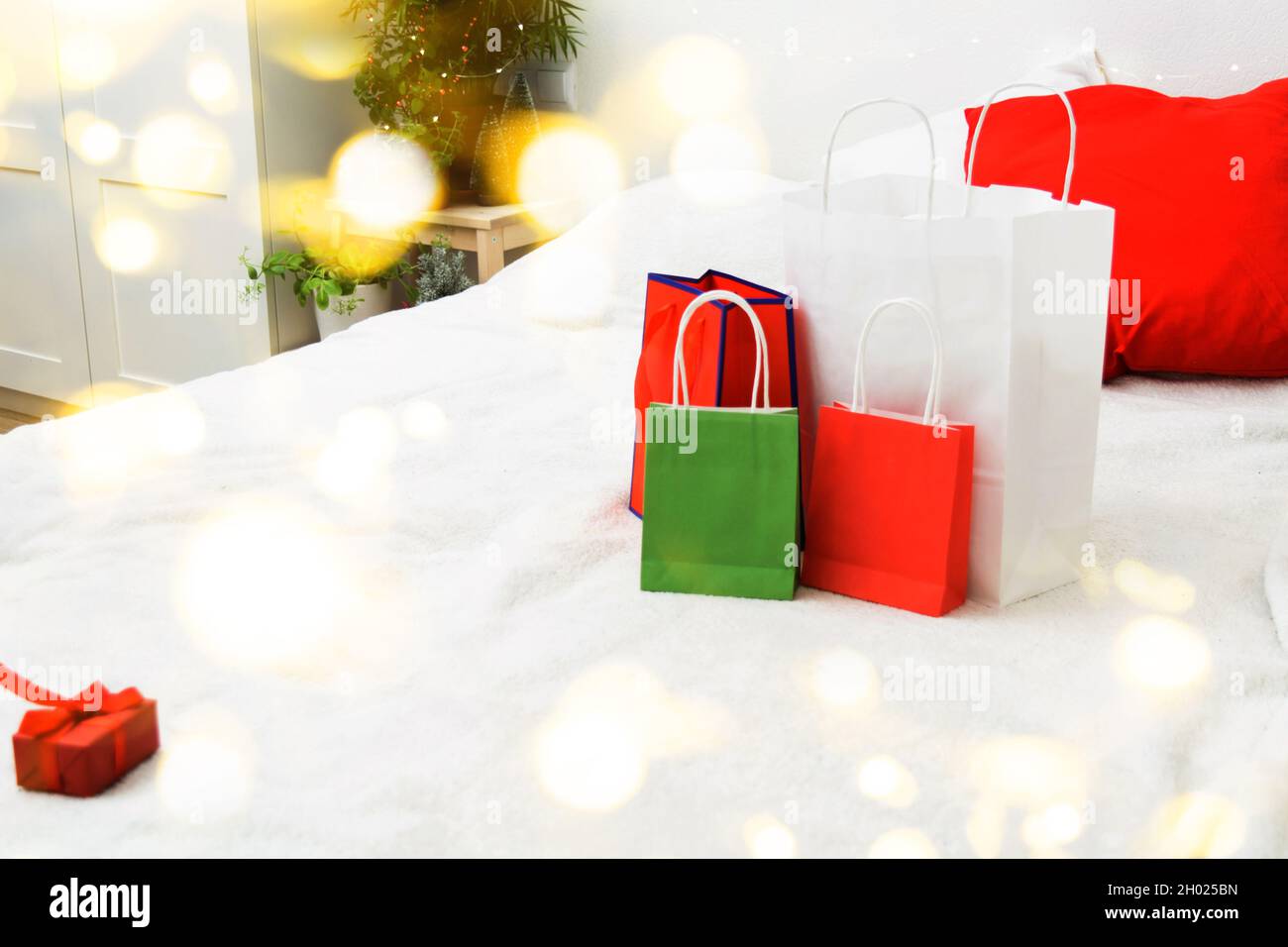 Weihnachts-Shopping-Konzept mit Papiertüten und Geschenkbox auf dem Bett zu Hause Stockfoto