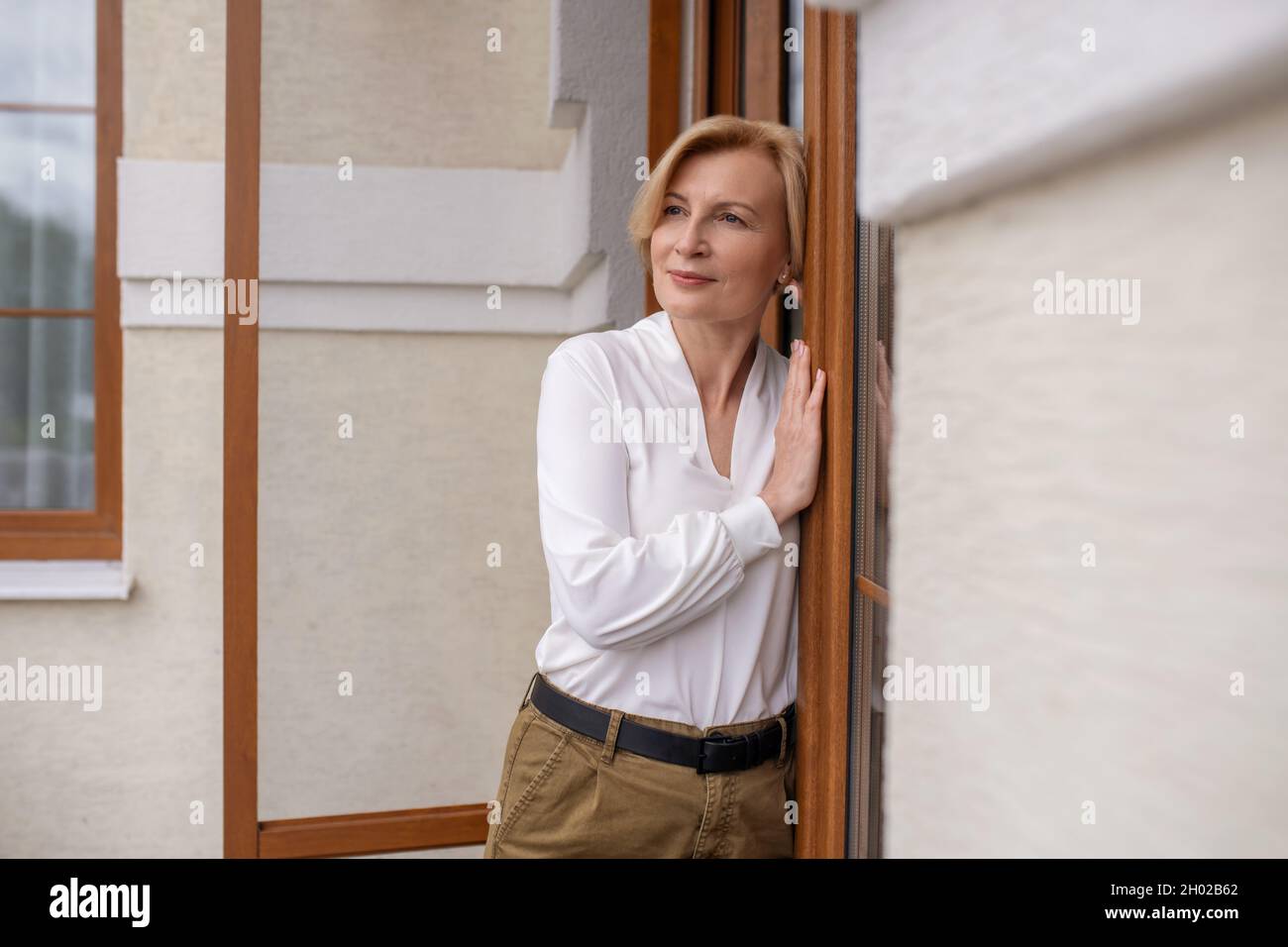 Nachdenkliche, ruhige Frau, die an der Außentür steht Stockfoto