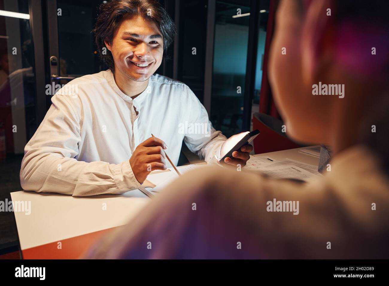 Lächelnder Mann, der am Arbeitsplatz mit Frau zusammen arbeitet Stockfoto