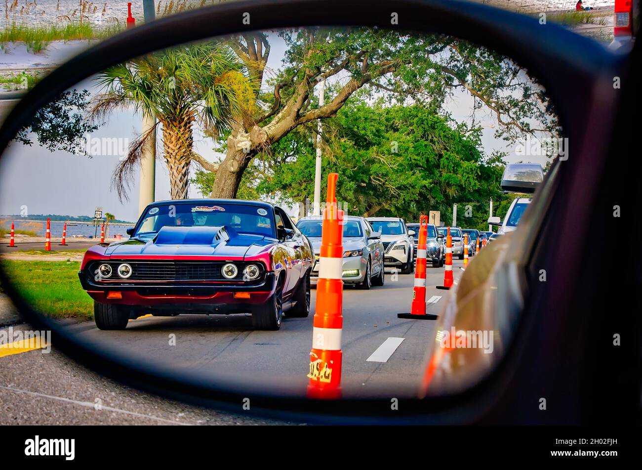 Ein Oldtimer spiegelt sich im Seitenspiegel eines Autos auf dem Highway 90 während der 25. Jährlichen Cruisin’ the Coast Oldtimer Show in Biloxi wider. Stockfoto