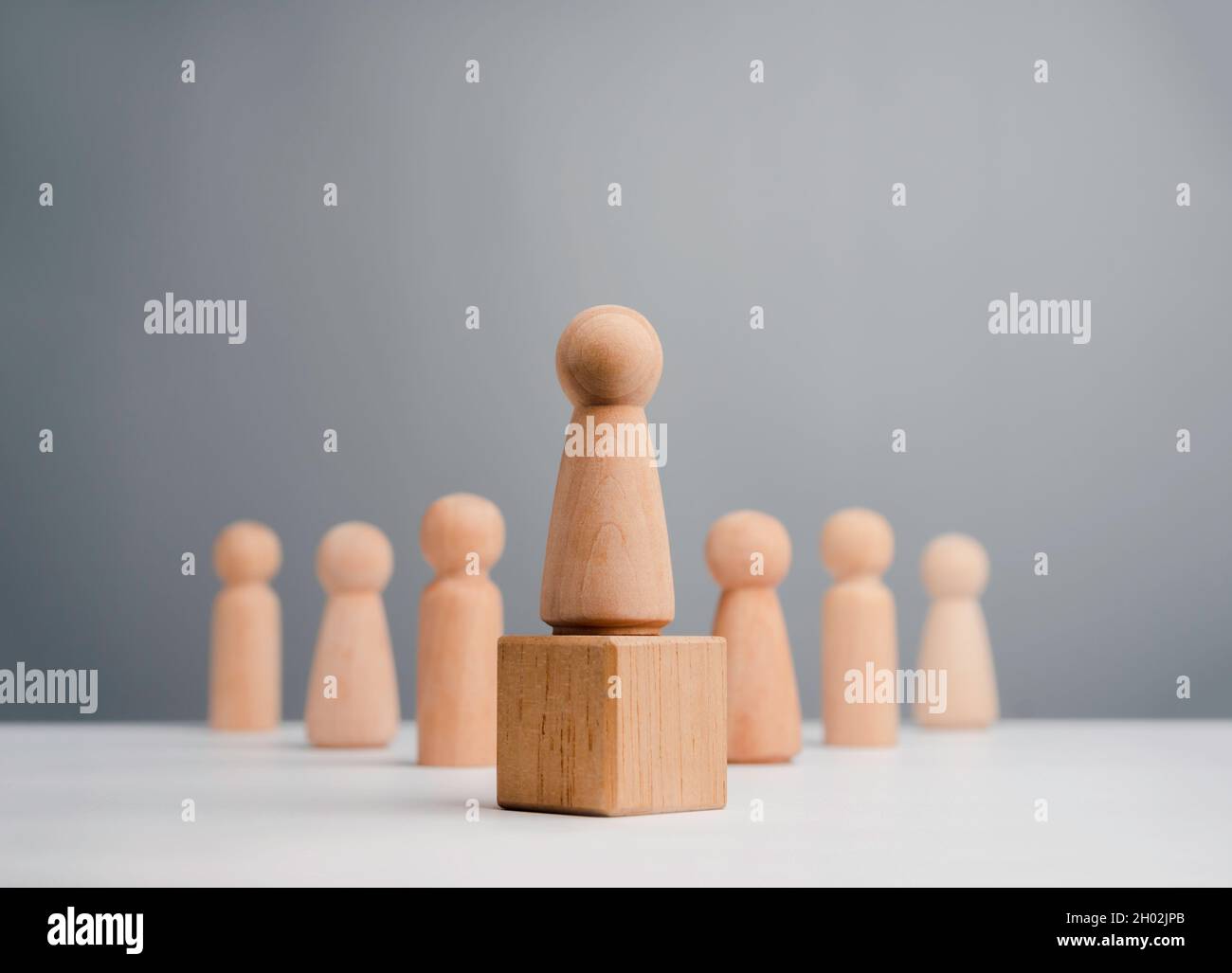 Führungspersönlichkeit Frau, Influencer, Frauen in Führungsposition Konzept. Holzfigur, starkes Weibchen, das auf der Kiste und im Team steht, minimalistischer Stil. Stockfoto