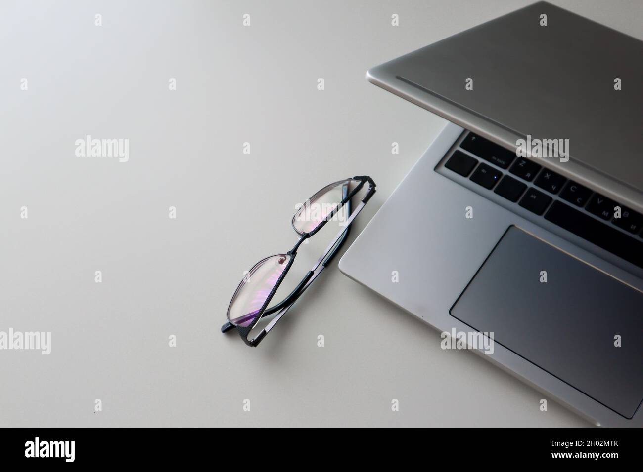 Arbeitsplatz zu Hause mit Laptop und Brille. Minimalismus flach Stockfoto