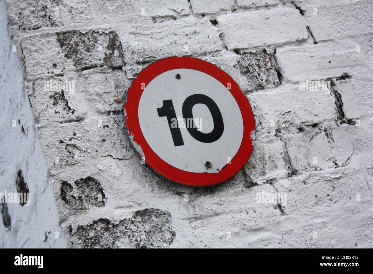 Schild mit der Nummer 10 auf einer gemalten Ziegelwand. Stockfoto