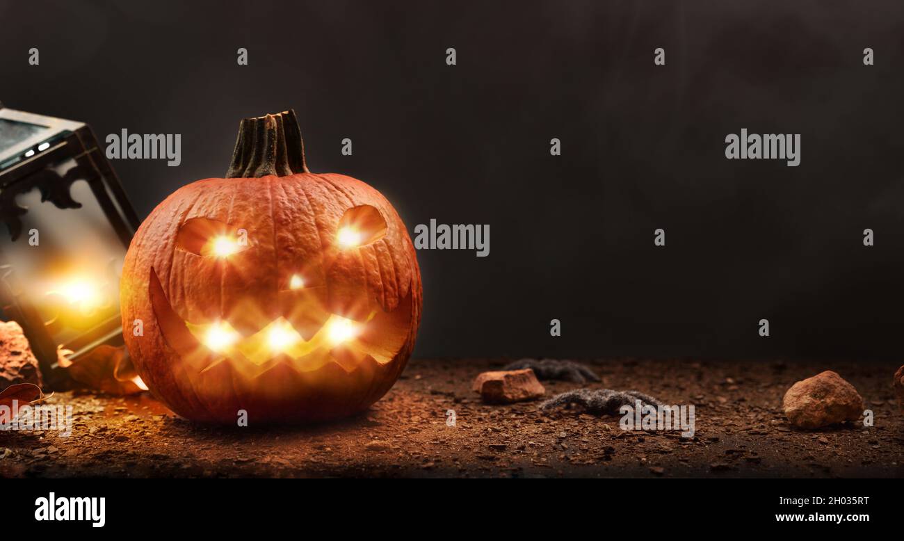 Halloween mit geschnitztem und beleuchteten Kürbis mit Spinnen und Laterne isoliert schwarzen Hintergrund. Vorderansicht. Horizontale Zusammensetzung. Stockfoto