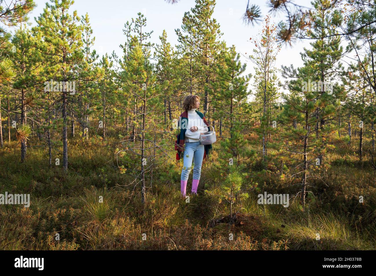 Casual Mädchen in Gummistiefeln genießen warmen sonnigen Tag Spaziergang Pick Cranberries im Herbst Wald. Herbstsaison Stockfoto