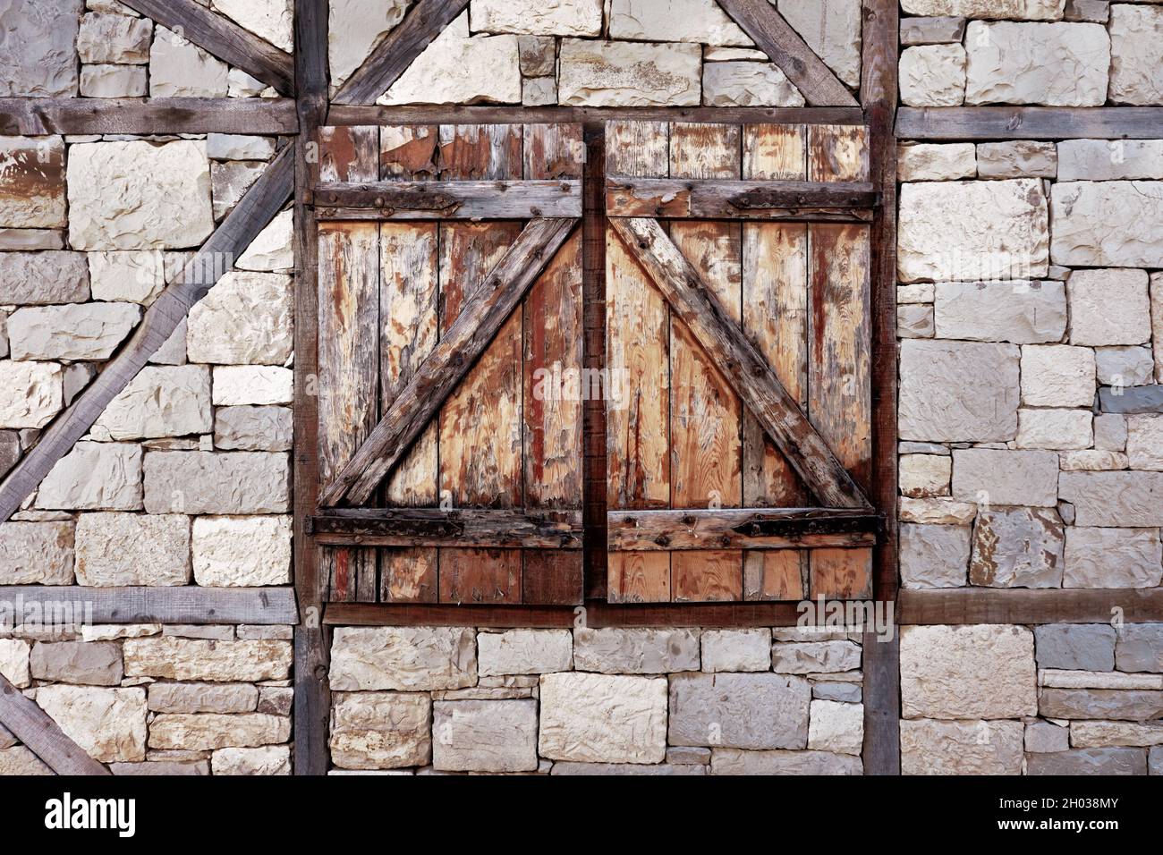 Altes Fenster mit geschlossenen Holzjalousien an Steinwänden. Antike griechische Architektur. Stockfoto