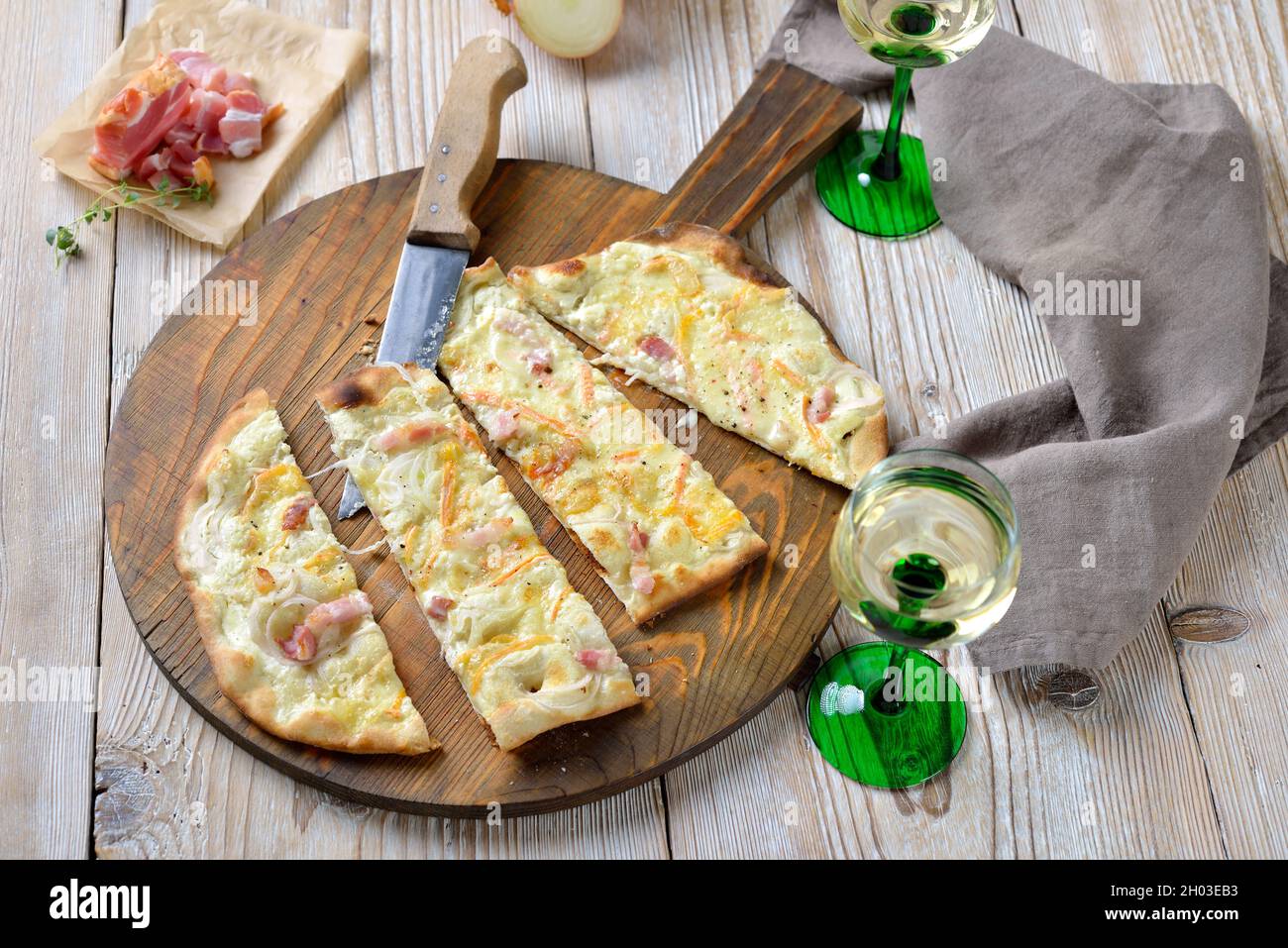 Herzhafte Flammkuchen aus dem Elsass mit Zwiebeln, geräuchertem Speck und  aus dem Ofen heißer münsterkäse, serviert mit elsässischen Weißwein  Stockfotografie - Alamy