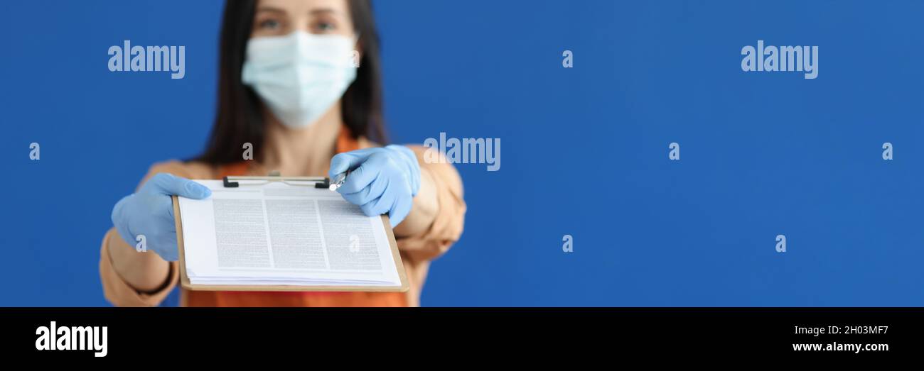 Kellnerin in schützender medizinischer Maske und Handschuhen, die Zwischenablage mit Dokumenten und Stift zur Unterschrift aus der Nähe geben Stockfoto