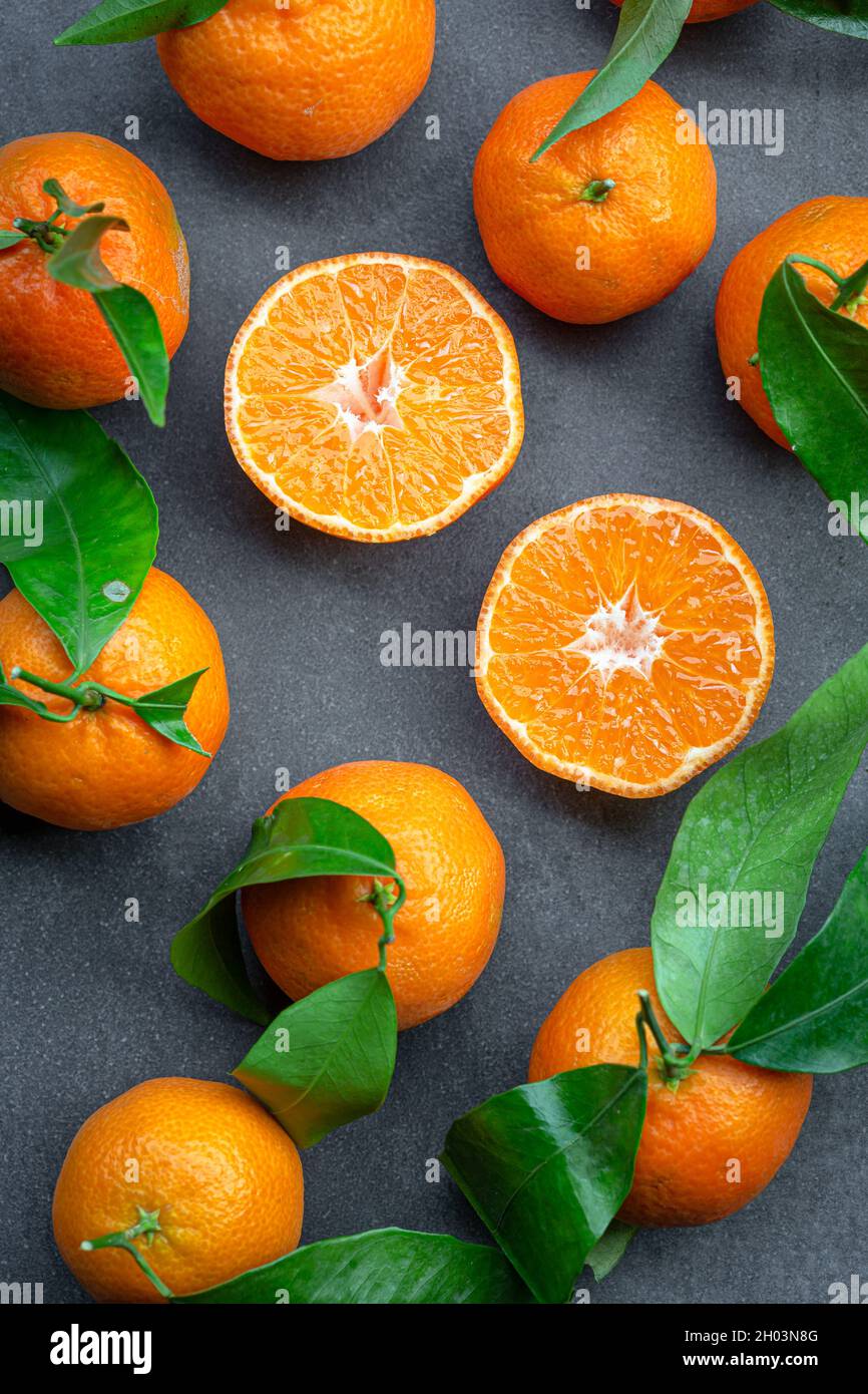 Halb und ganz Clementine und Blatt auf dunklerem Hintergrund Stockfoto