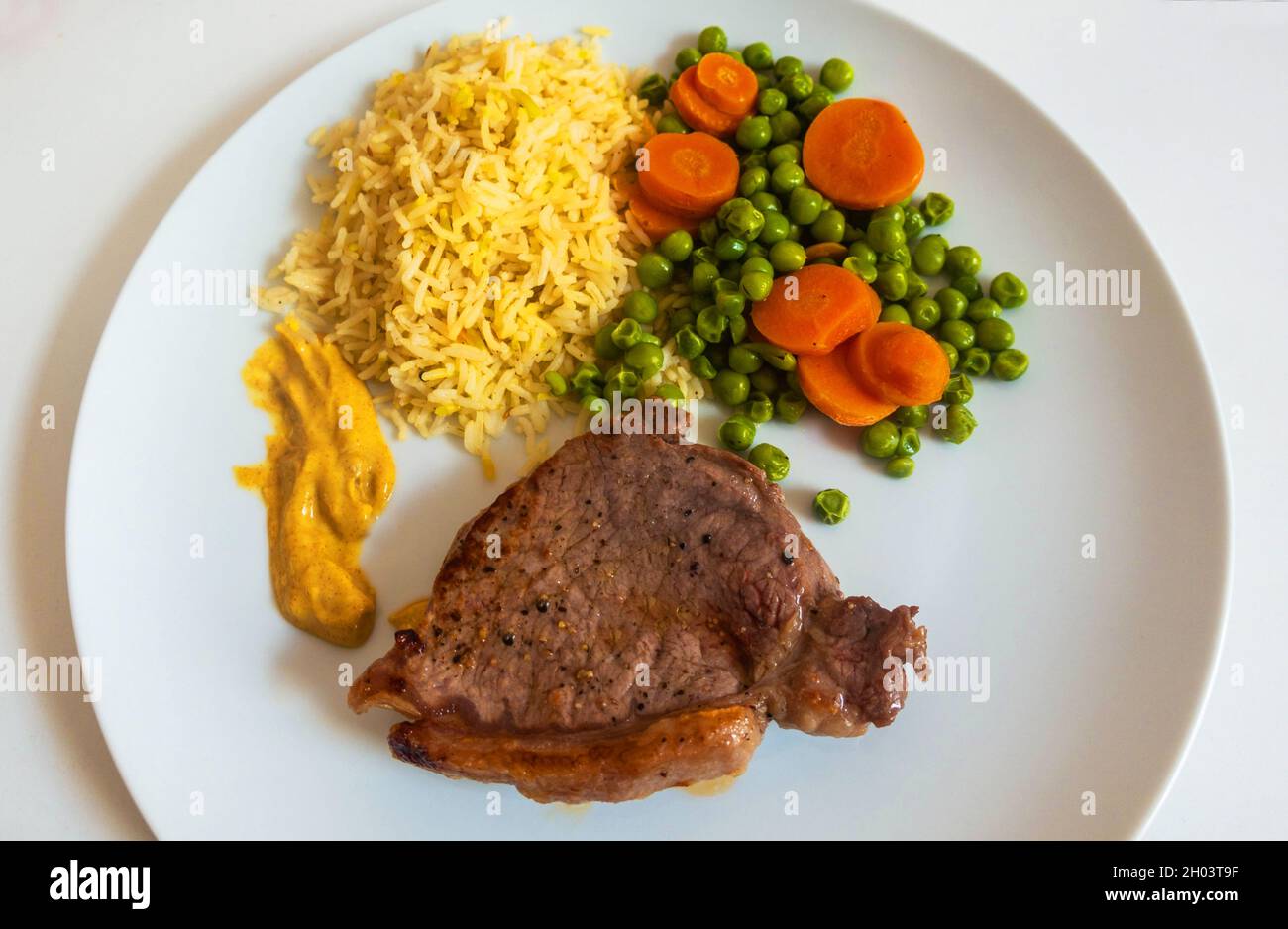 Lendensteak mit Erbsen und Karotten sowie Reis und Dijon-Senf Stockfoto