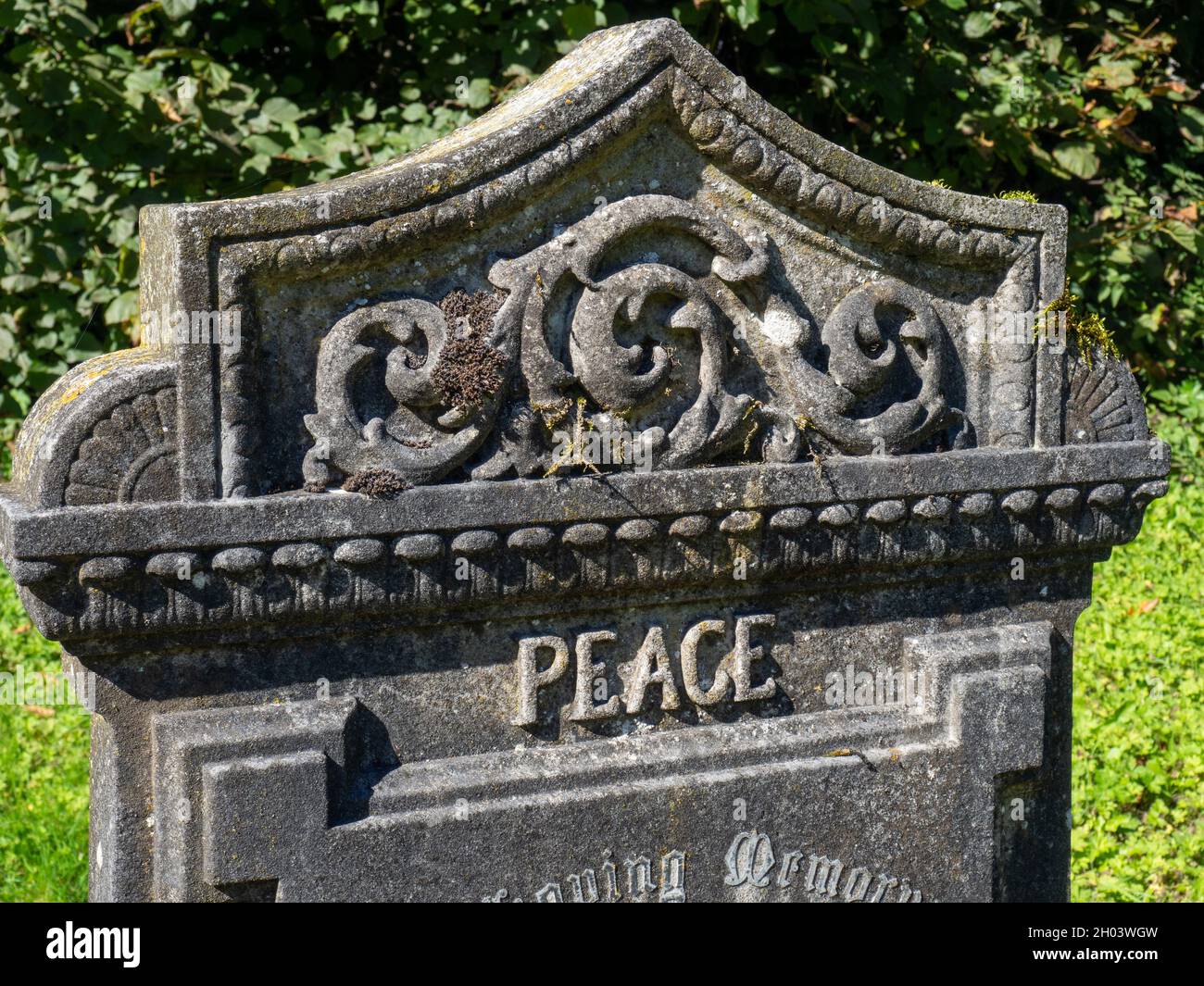 Ein alter geschnitzter Grabstein, der mit dem Wort Frieden beschriftet ist, auf dem Kirchhof des heiligen Johannes des Täufers im Dorf Chelmorton, Derbyshire, Großbritannien Stockfoto
