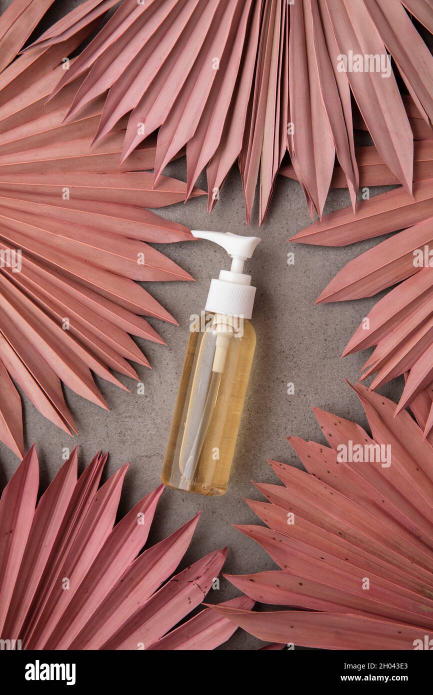 Natürliche Schönheit Produkthintergrund mit einer Flasche und getrockneten rosa Palmblättern Stockfoto