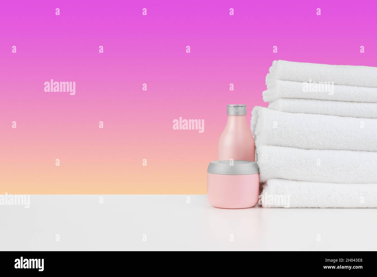 Stapel Handtücher, Flaschen mit Shampoo auf weißem Tisch Stockfoto