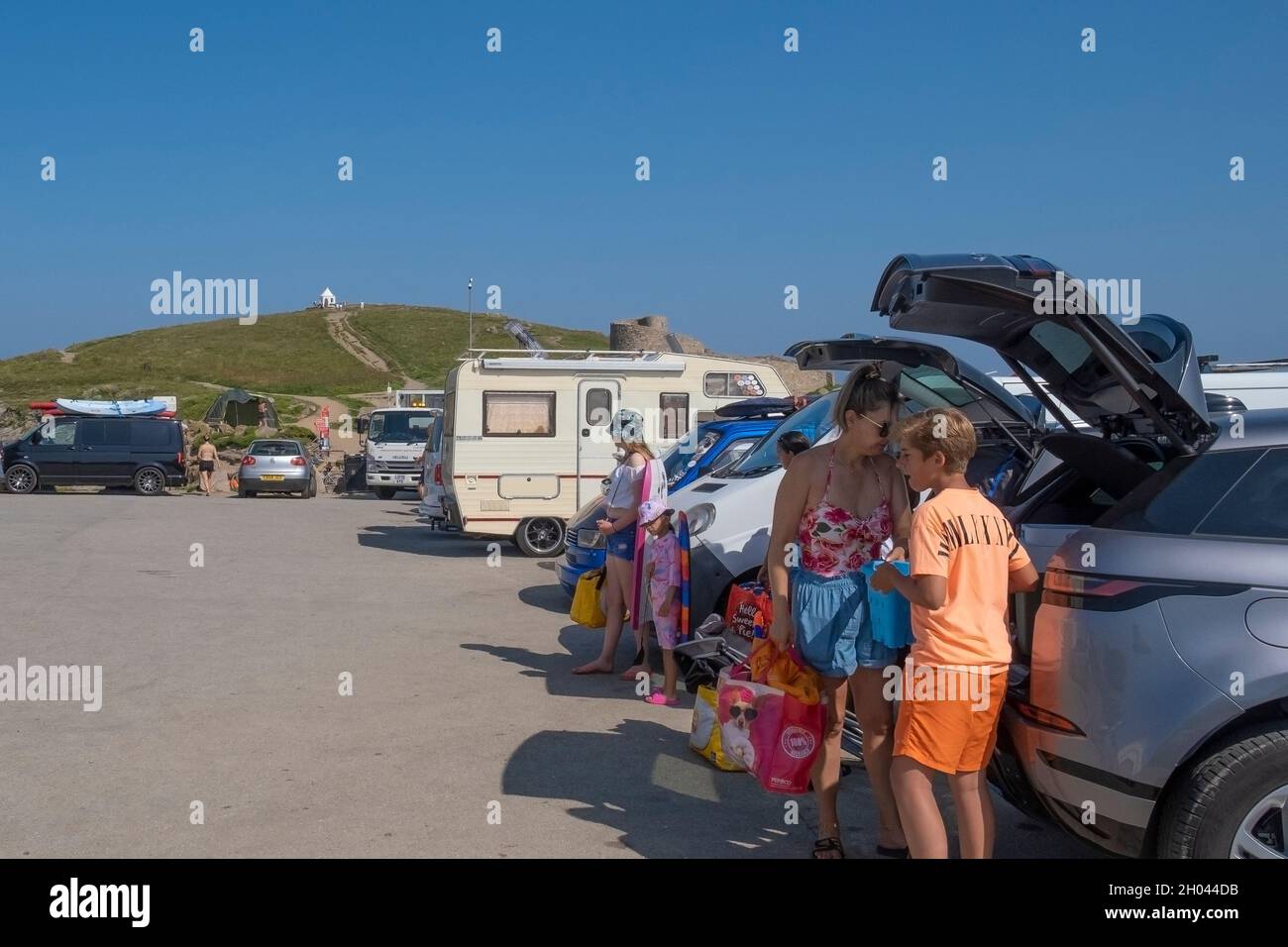 Glückliche Urlauber beanspruchen den letzten Parkplatz auf einem vollen Parkplatz in Towan Head in Newquay in Cornwall. Stockfoto