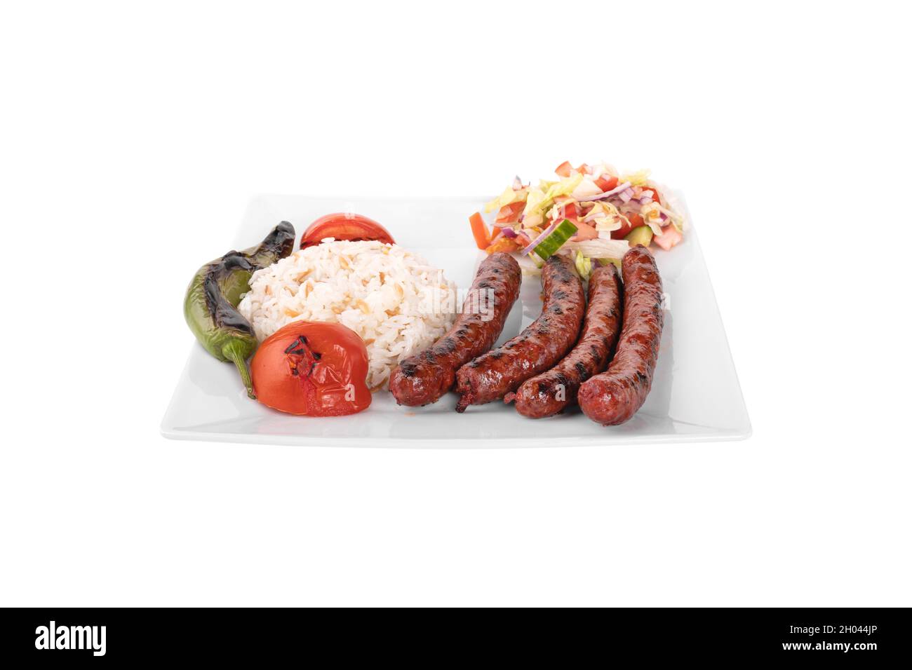 Merguez, gegrillter Merguez mit Gemüse, Reis in einem Porzellan-Servierteller auf weißem Hintergrund. Stockfoto