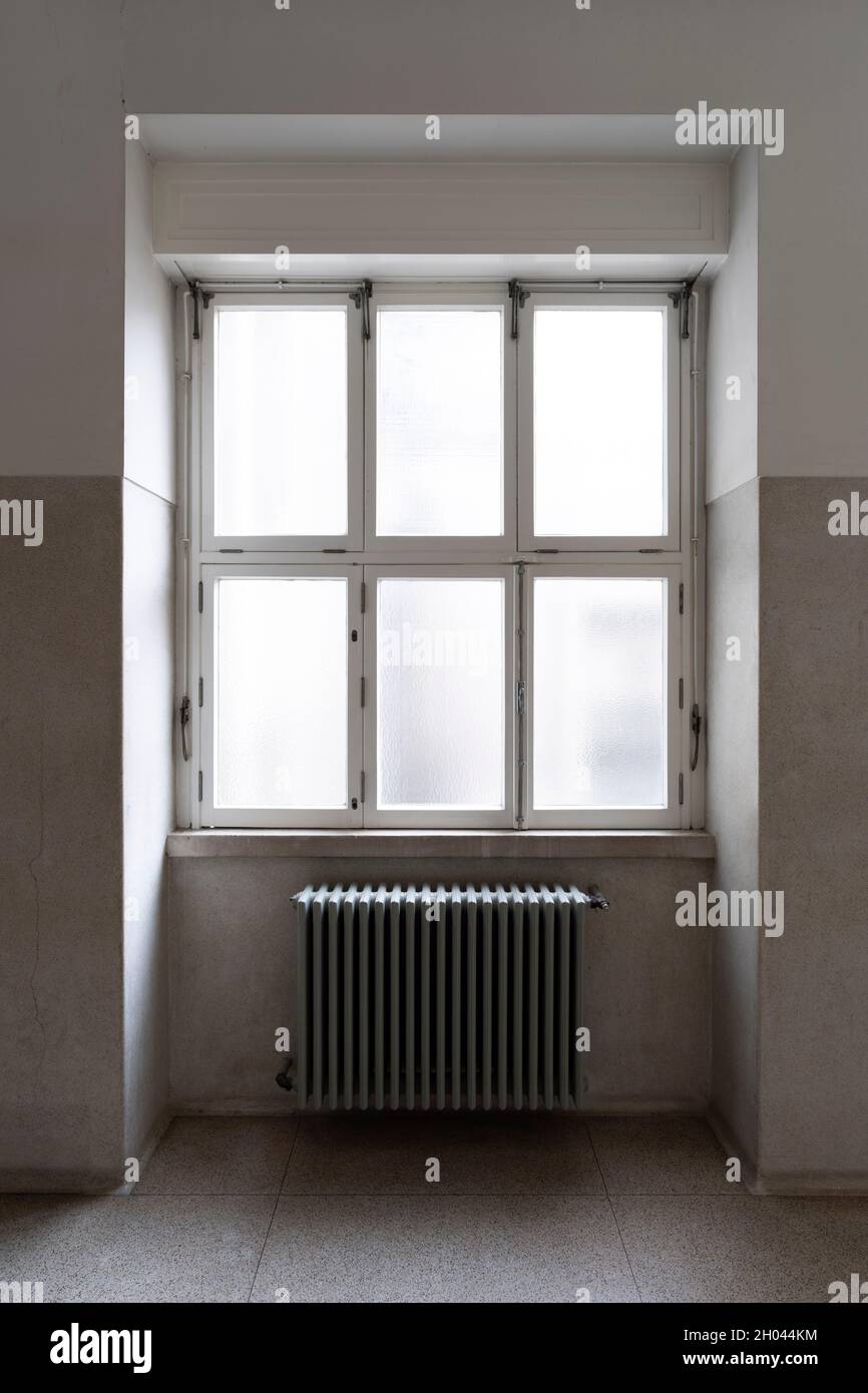 Alte metallische Heizkörper unter einem großen Fenster montiert Stockfoto