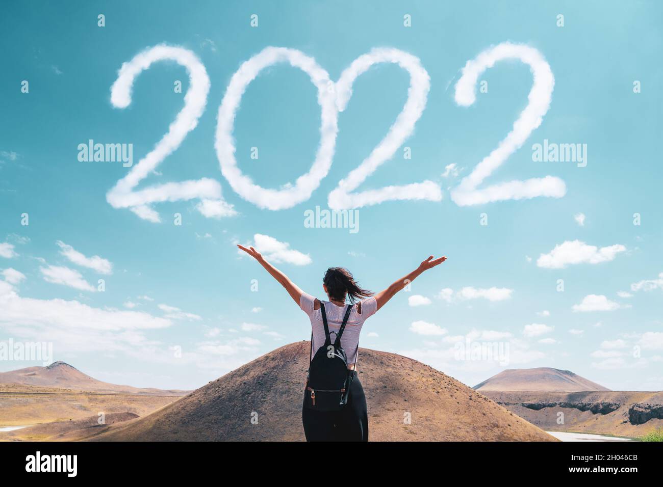 Brunette Frau begrüßt die 2022 gegen Wolken. Stockfoto