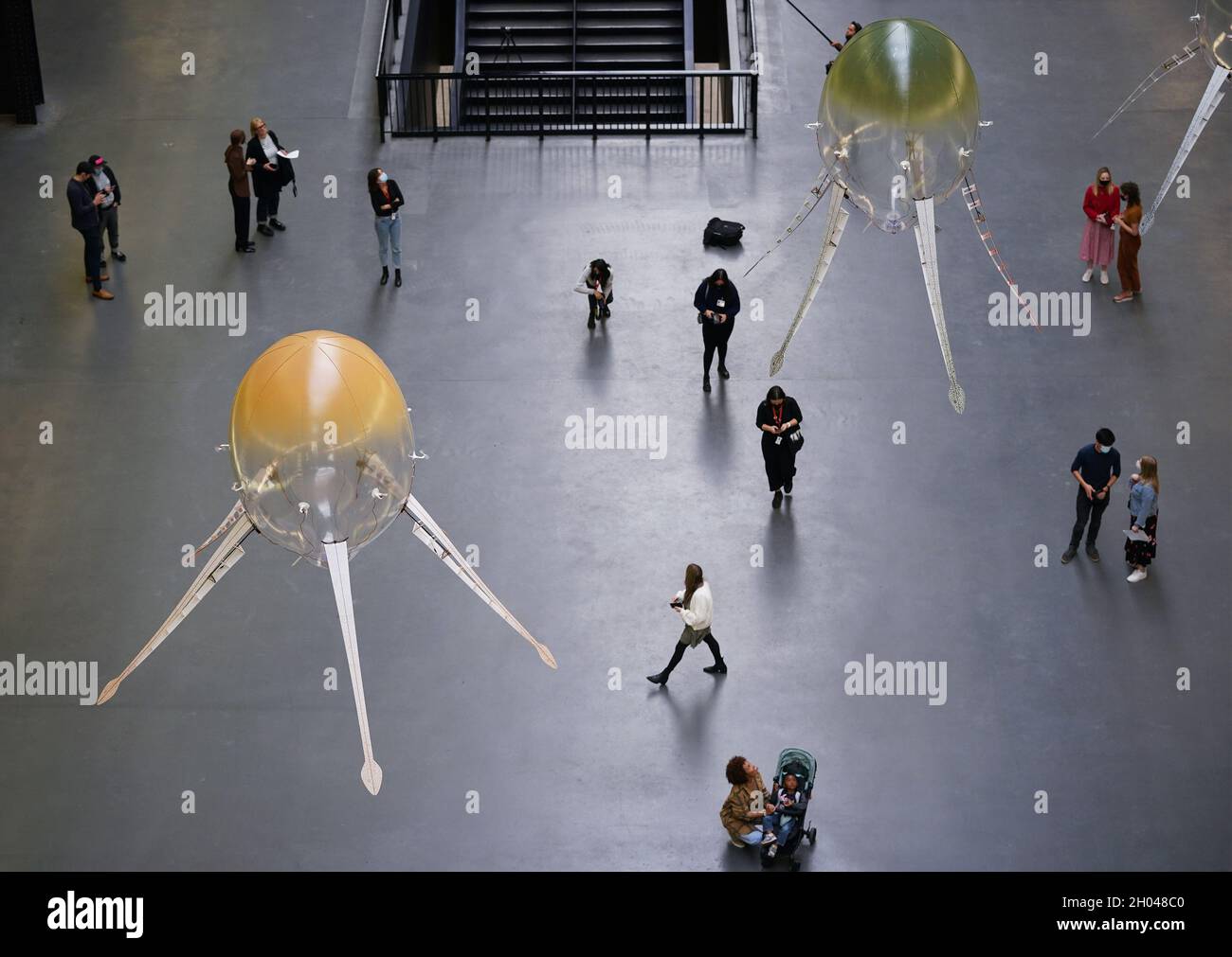 Besucher, die sich zwei Arten von schwimmenden Maschinen angeschaut haben - die sogenannten Aerobes, die mit Helium gefüllt sind, von Rotoren angetrieben und von einem kleinen Batteriepack angetrieben werden, Und reagieren auf verschiedene Elemente ihrer Umgebung - während der Tate Modern-Presseansicht in London für die Hyundai-Kommission, die von Anicka Yi durchgeführt wurde. Bilddatum: Montag, 11. Oktober 2021. Stockfoto