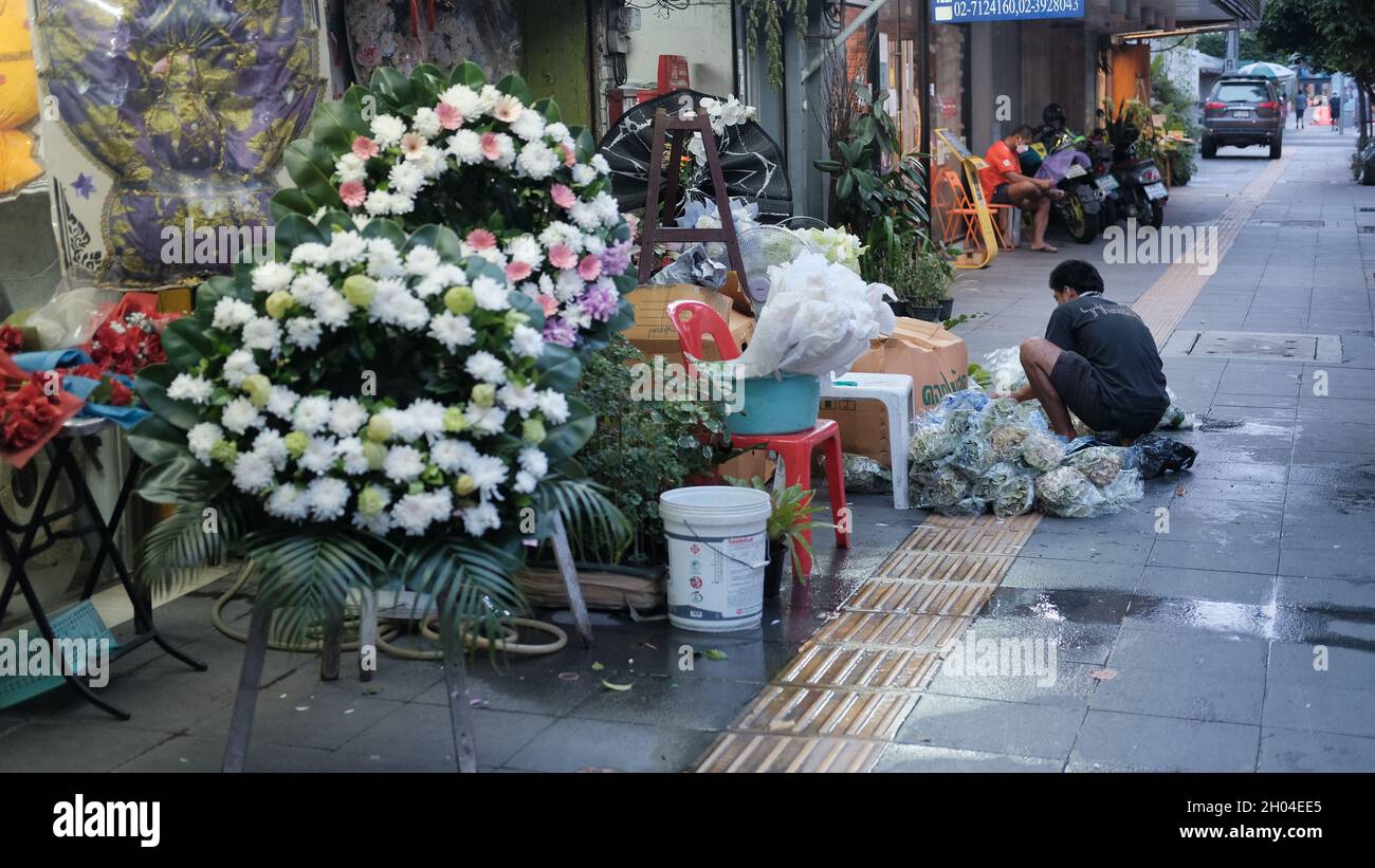 Mann, der am Bürgersteig des Blumenlades auf der Sukhumvit Road in der Nähe der Bushaltestelle Ekkamai Bangkok Thailand arbeitet Stockfoto