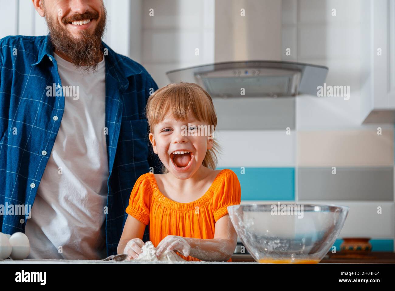 Glückliche Familie Tochter und Vater Spaß lachen Lächeln beim Kochen Essen in der Küche Innenraum. Kind Mädchen Tochter knetet Mehlteig in der Nähe Vater Stockfoto